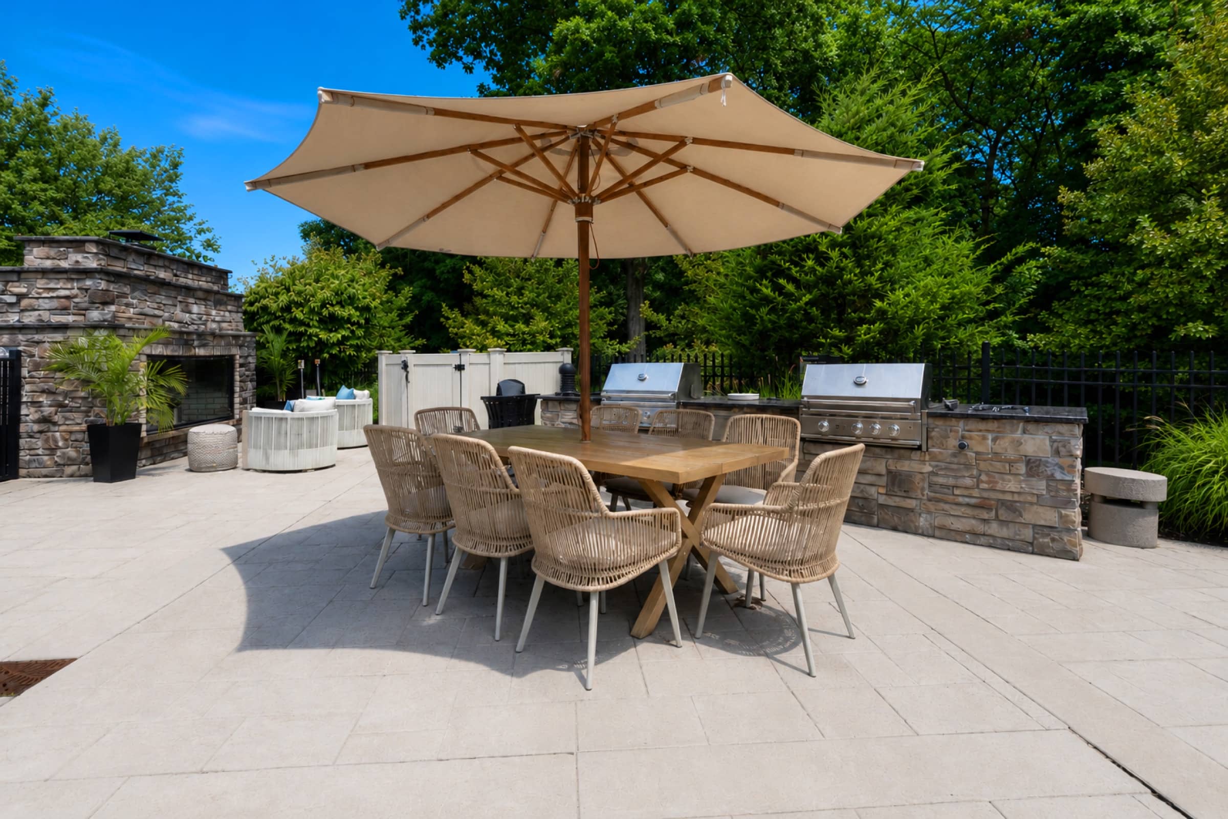 Al fresco dining table under an umbrella beside the White Oaks outdoor kitchen