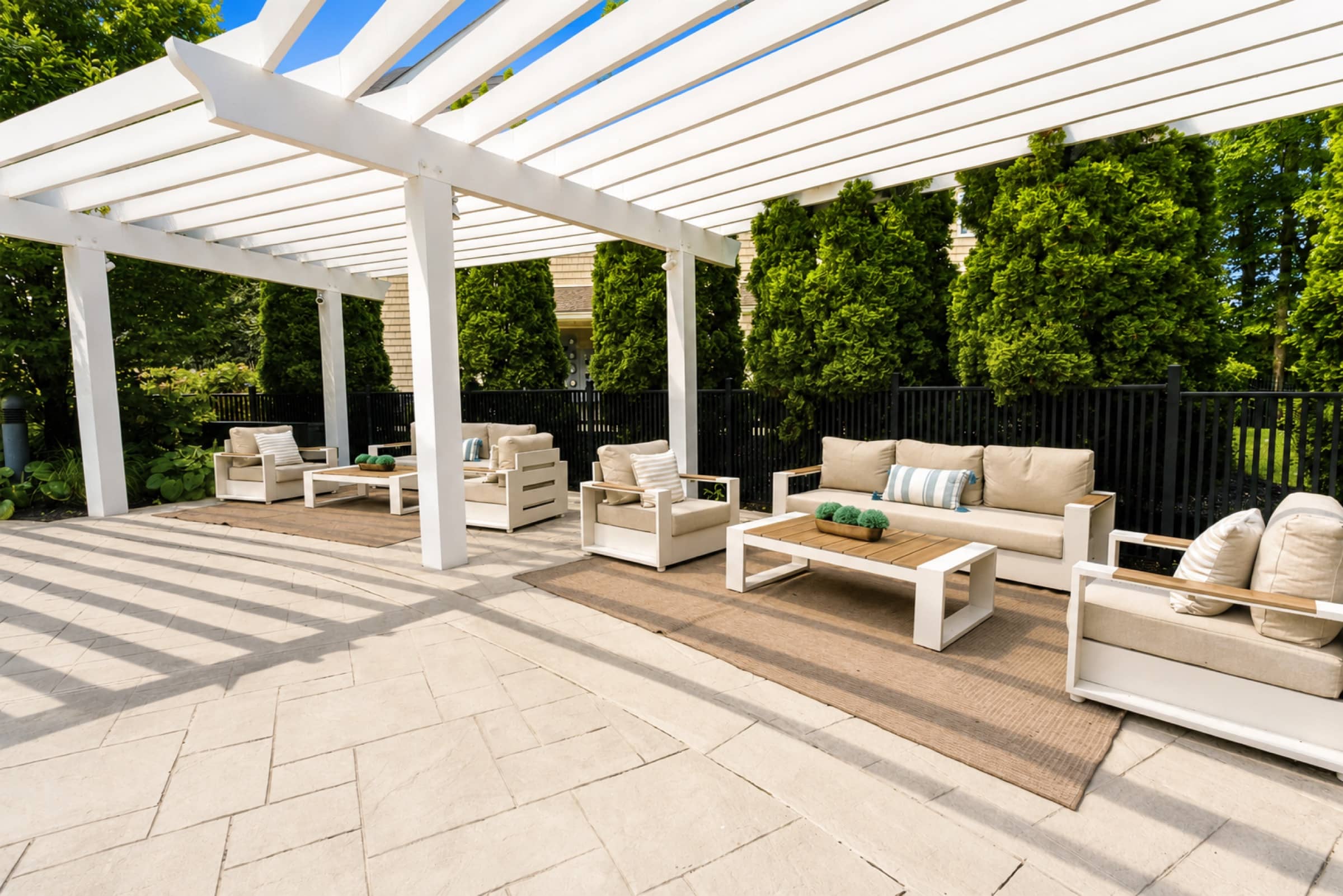 White pergola cabanas with cushioned lounge seating beside the White Oaks pool
