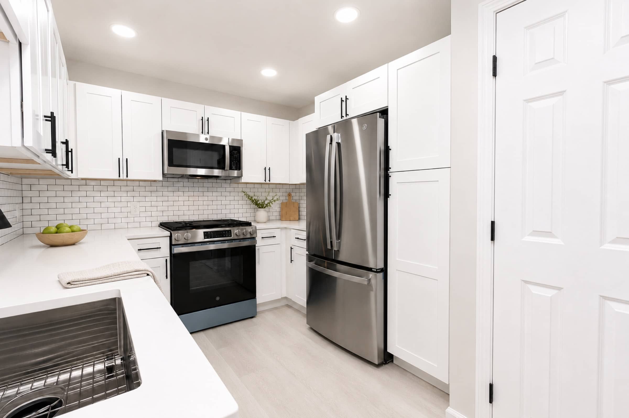 Kitchen with stainless refrigerator and gas range at White Oaks (virtually staged)